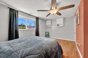 Bedroom with ceiling fan, a textured ceiling, and light LVP flooring