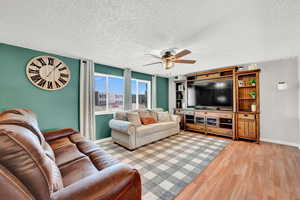 Living room with a textured ceiling, light  LVP, and ceiling fan