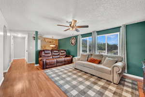 Living room with ceiling fan, a textured ceiling, and light LVP flooring