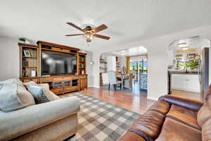 Living room featuring a textured ceiling, ceiling fan, sink, and light LVP flooring