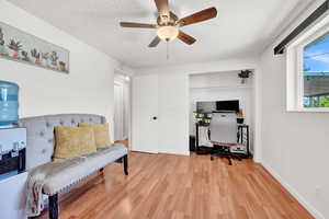 Office space featuring ceiling fan, light LVP flooring, and a textured ceiling