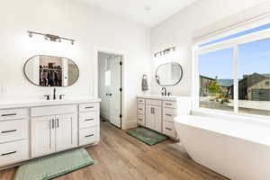 Primary Bathroom with a tub, plenty of natural light, vanity, and wood-type flooring