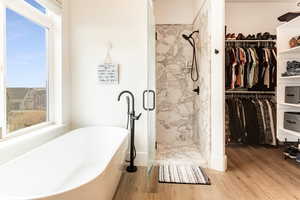 Primary Bathroom featuring independent shower and bath and hardwood / wood-style flooring and one of 2 walk in closets