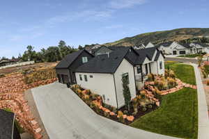 View of side of property featuring a lawn, a mountain view, and a garage