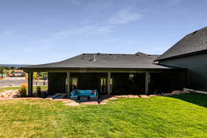 Back of property with an outdoor living space, a patio, and a lawn