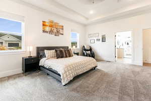 Primary Bedroom featuring carpet floors, a tray ceiling, and ensuite bath