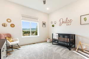 Bedroom 2 featuring ceiling fan, a nursery area, and light colored carpet