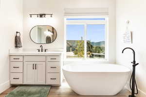 Primary Bathroom with a bathing tub, vanity, and wood-type flooring