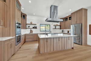 Kitchen with a spacious island, island exhaust hood, light hardwood / wood-style flooring, stainless steel appliances, and tasteful backsplash