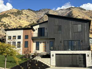 Contemporary house featuring a balcony, a garage, and a mountain view