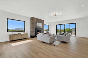 Living room with a chandelier, a fireplace, and light hardwood / wood-style floors