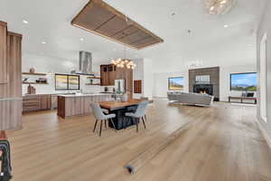 Dining space featuring light hardwood / wood-style flooring, a tile fireplace, and an inviting chandelier