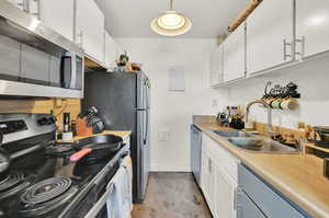 Kitchen with hanging light fixtured, white cabinetry, appliances with stainless steel finishes.