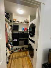 Laundry room featuring stacked washer / drying machine and light hardwood / wood-style flooring