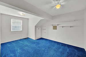 Additional living space featuring dark colored carpet and ceiling fan