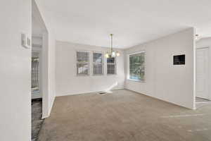 Unfurnished dining area with light carpet and a chandelier