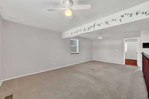 Unfurnished living room featuring carpet flooring and ceiling fan