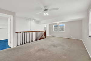 Carpeted empty room featuring track lighting and ceiling fan