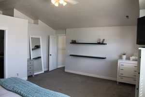 Carpeted bedroom with ceiling fan and vaulted ceiling