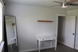 Unfurnished bedroom featuring dark colored carpet and ceiling fan