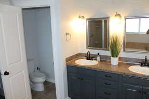 Bathroom featuring toilet, vanity, walk in shower, and tile patterned floors