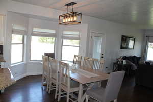 Dining area with a notable chandelier, a healthy amount of sunlight, and dark hardwood / wood-style floors