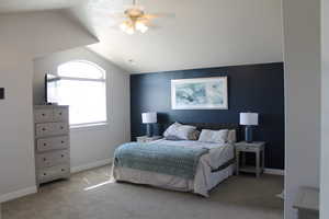 Bedroom with ceiling fan, light carpet, and lofted ceiling