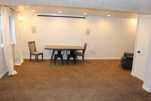 Dining space featuring a textured ceiling and dark colored carpet