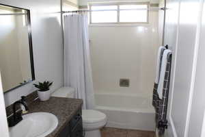 Full bathroom with tile patterned flooring, vanity, shower / tub combo, and toilet