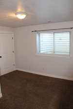 Carpeted spare room with a textured ceiling and a healthy amount of sunlight