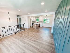 Unfurnished living room with a textured ceiling, light hardwood / wood-style flooring, and a chandelier