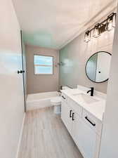 Full bathroom with vanity, a textured ceiling, tile walls, toilet, and tiled shower / bath combo