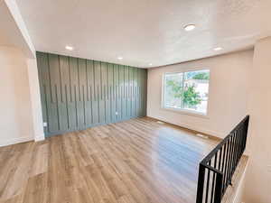 Empty room featuring light wood-type flooring and a textured ceiling