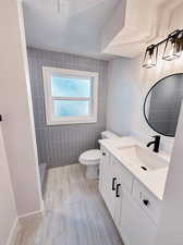 Bathroom with tile patterned flooring, toilet, vanity, and tile walls