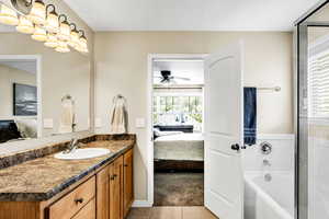 Bathroom featuring ceiling fan, tile patterned flooring, separate shower and tub, and vanity