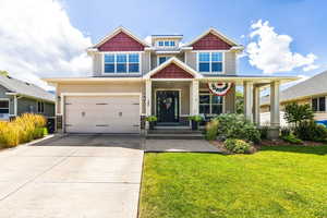 Craftsman-style house featuring a porch, a garage, and a front lawn