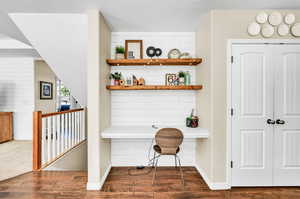 Interior space with vaulted ceiling, built in desk, and dark wood-type flooring