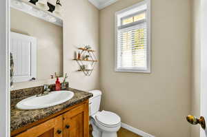 Bathroom featuring toilet, crown molding, and vanity