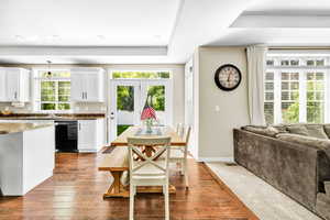 Dining area with wood-type flooring, a tray ceiling, and a healthy amount of sunlight