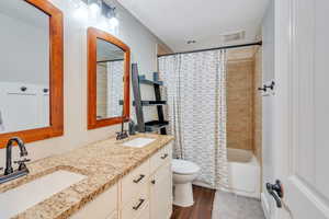 Full bathroom with shower / bath combo with shower curtain, vanity, hardwood / wood-style floors, and toilet