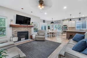 Living room with a wealth of natural light, ceiling fan, light hardwood / wood-style floors, and a fireplace