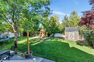 View of yard with a trampoline, a shed, and a playground