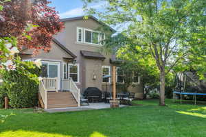 Rear view of house with a lawn, a trampoline, and a patio area