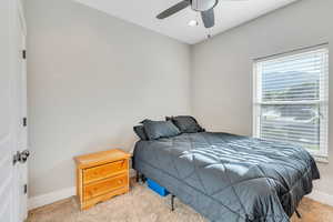 Carpeted bedroom with ceiling fan and multiple windows