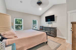 Bedroom featuring ceiling fan, light hardwood / wood-style floors, and lofted ceiling