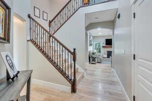 Staircase with hardwood / wood-style floors and a stone fireplace