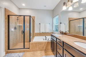 Bathroom featuring plus walk in shower, vanity, and tile patterned floors