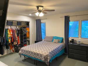 Carpeted bedroom with a closet and ceiling fan