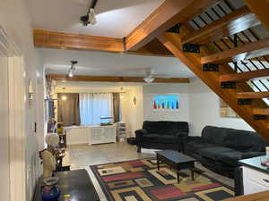 Tiled living room with ceiling fan and beamed ceiling