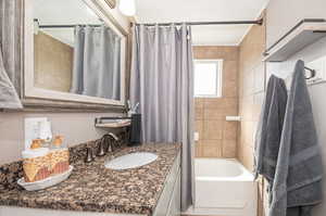 Bathroom featuring shower / tub combo with granite vanity